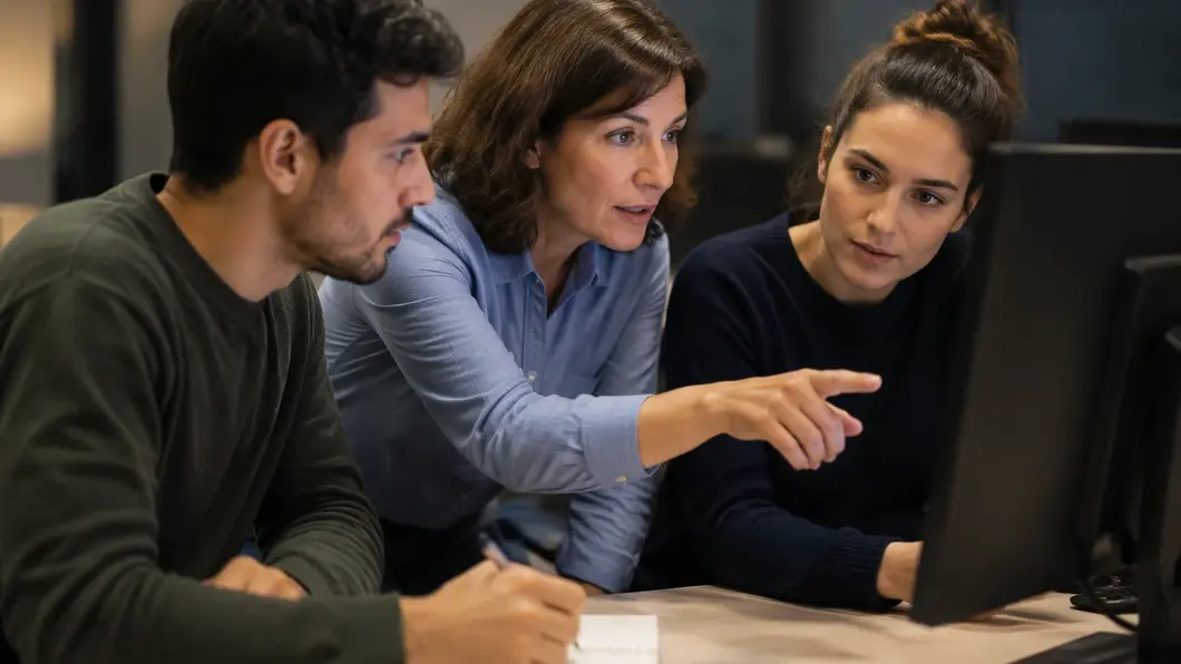 Responsable métier et développeurs vérifiant ensemble un changement logiciel sur un écran